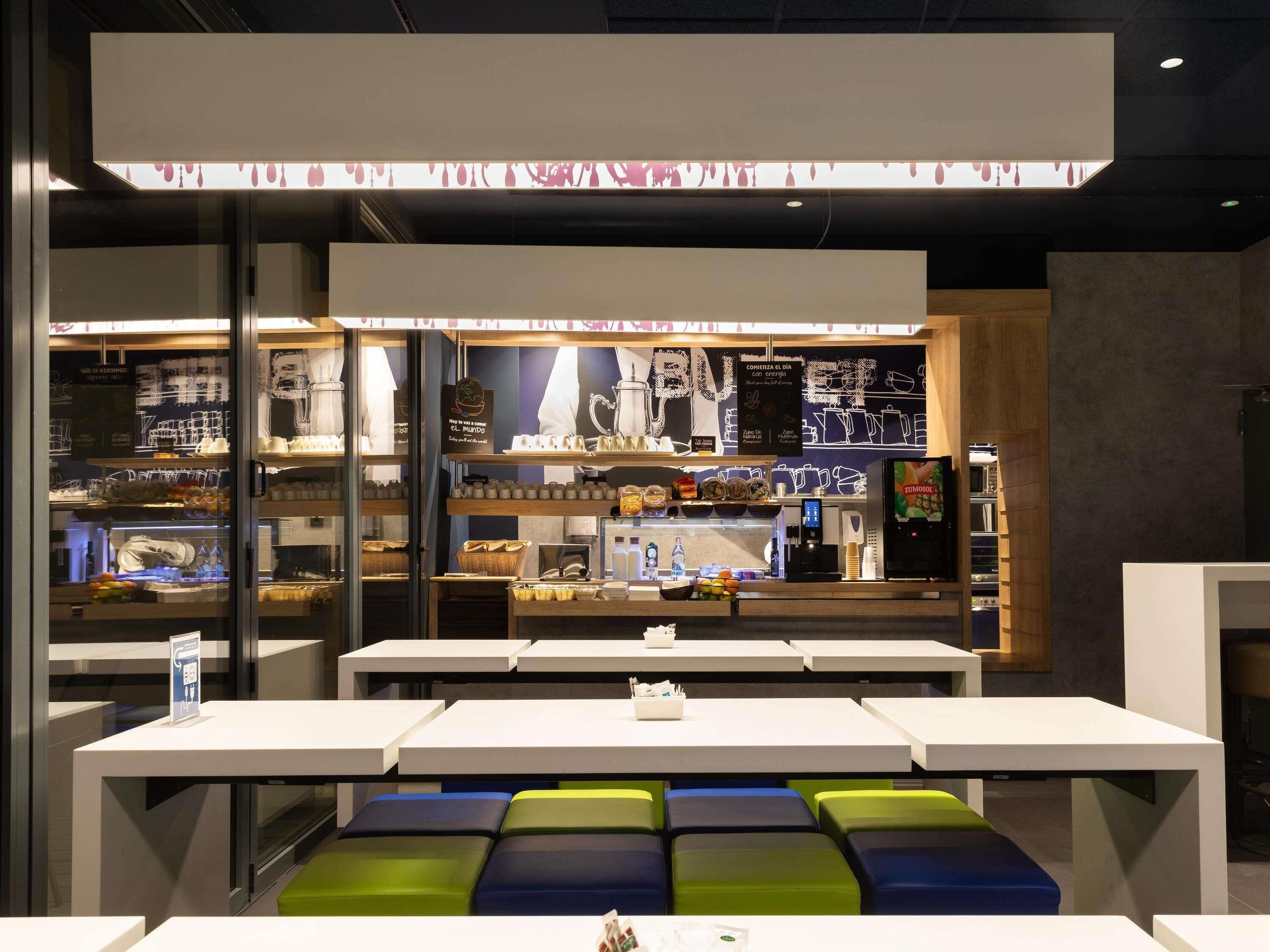 A modern café with a glass display case, seating area, and a menu board.