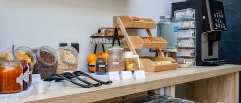 A coffee shop counter with jars of granola, honey, and other spreads, a coffee machine, and a bread display.