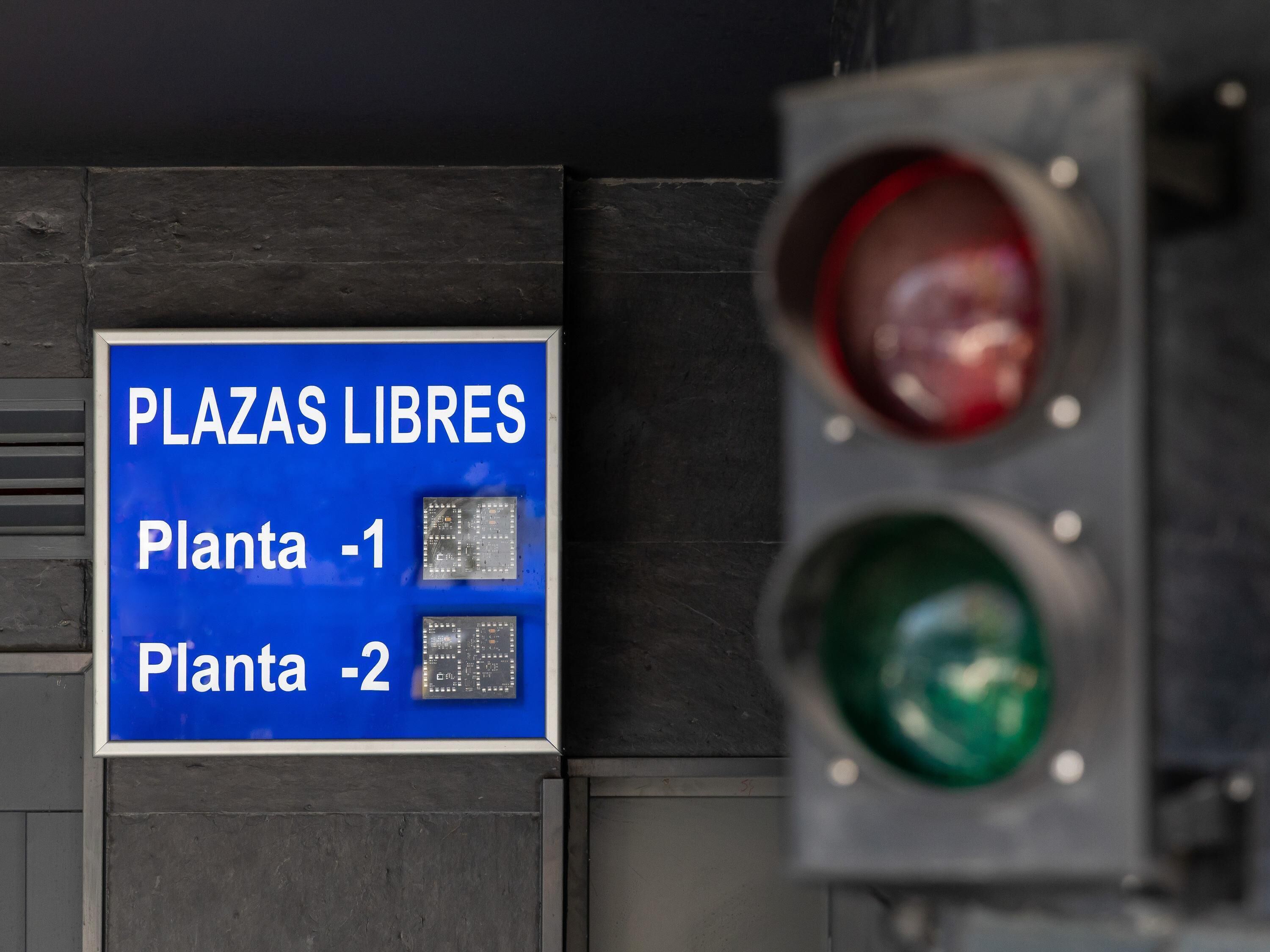 Een verkeerslicht en een bord met 'PLAZAS LIBRES' en twee plantennummers.