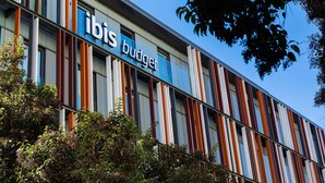 Un bâtiment arborant une enseigne « ibis budget » et présentant un design architectural moderne caractérisé par des lignes verticales.