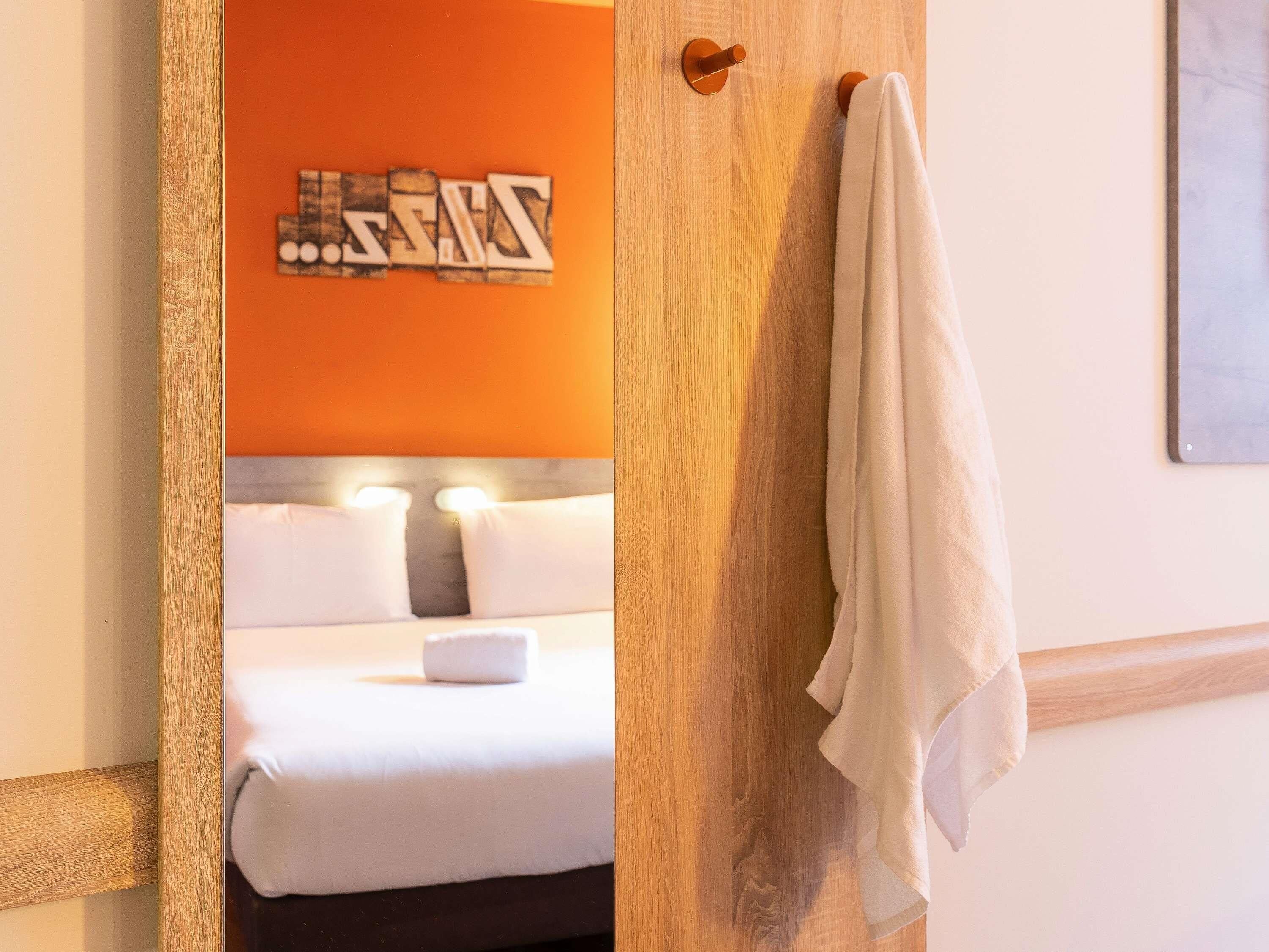 Ein Hotelzimmer mit einem Bett, einem Handtuchhalter und einer Wand mit einer Dekoration.