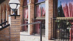 A brick building with large windows, a metal railing, and a street lamp. - Hotel Restaurante La Bodega (La Almunia de Dona Godina)