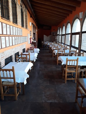 Un restaurante con paredes de ladrillo, cuadros enmarcados y mesas preparadas para comer.