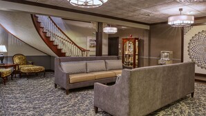 A hotel lobby with a grand staircase, a large sofa, a patterned carpet, and a decorative ceiling. - Carlisle Inn Walnut Creek (Millersburg)