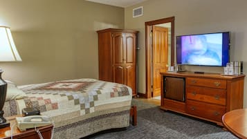 Una habitación de hotel con una cama, un armario de madera, un televisor y un escritorio con teléfono.