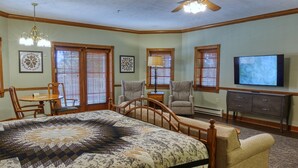 A bedroom with a large bed, two armchairs, a TV, and a ceiling fan. - Carlisle Inn Walnut Creek (Millersburg)