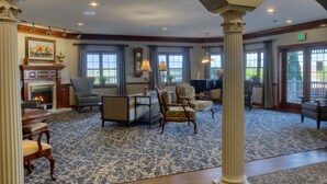 A spacious lobby with a fireplace, comfortable seating, and large windows. - Carlisle Inn Walnut Creek (Millersburg)