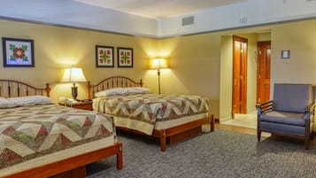 Habitación de hotel con dos camas, una silla y una puerta que da a otra habitación.