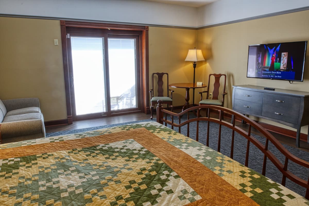 Une chambre d’hôtel avec un grand lit, un bureau, une télévision et une vue sur la ville par la fenêtre.