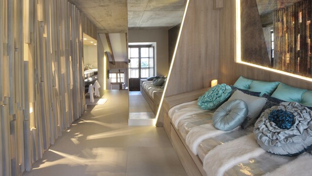 Un interior moderno con un pasillo largo y estrecho que conduce a una zona de estar con sofá y cojines.