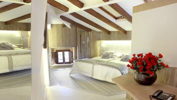 Un dormitorio con una cama grande, techo de madera y un florero con flores rojas sobre una mesita de noche.