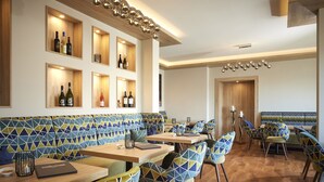 A modern restaurant interior with a geometric patterned bench, wooden tables, and chairs with a similar design. - Sporthotel Zum Hohen Eimberg (Willingen)