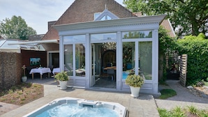 Una casa con piscina, un invernadero y un patio con mobiliario exterior.