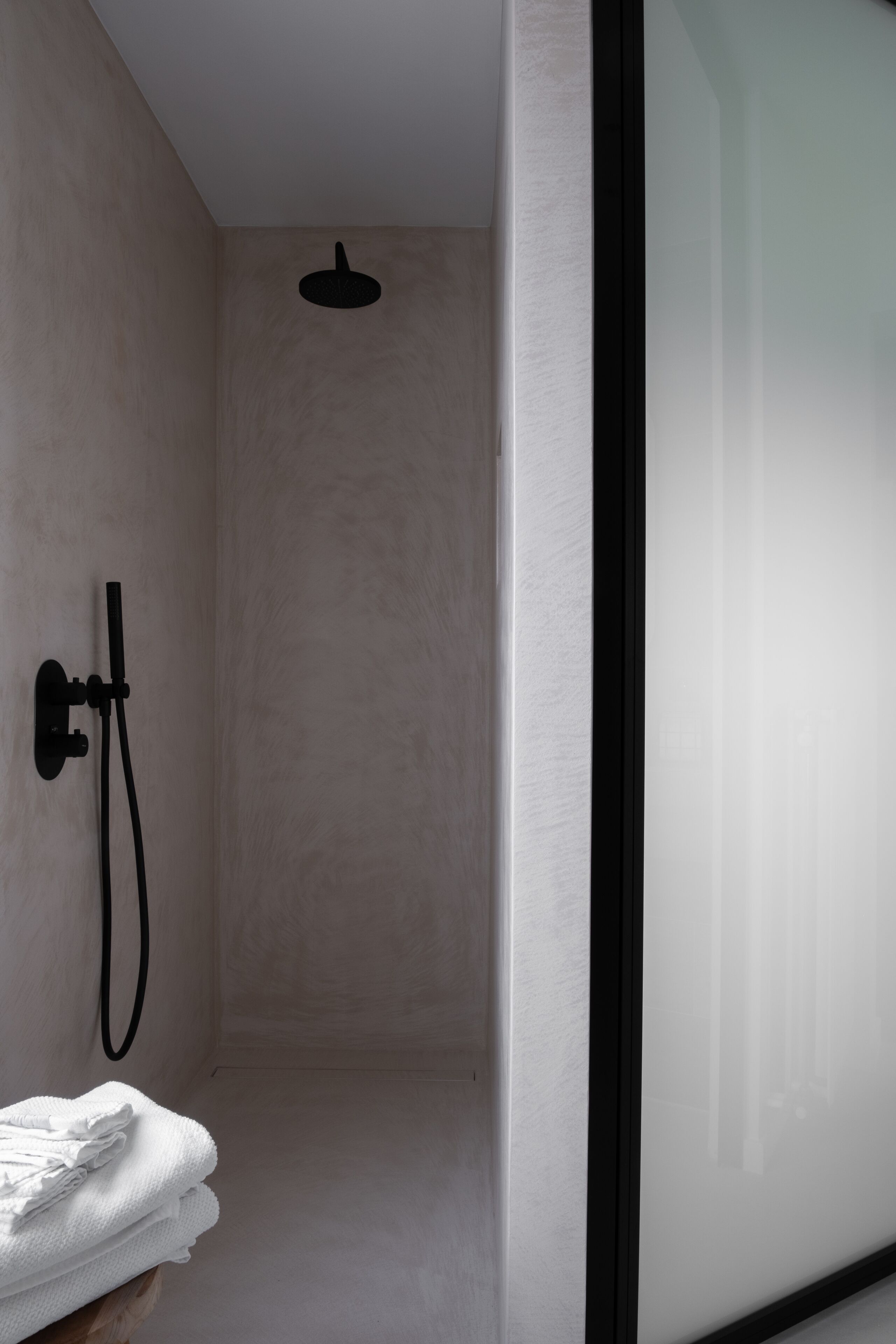 A modern bathroom with a glass shower enclosure, a towel rack, and a visible showerhead.