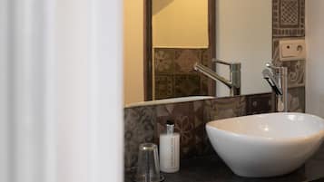 A bathroom with a large mirror, a white sink, and a towel rack.