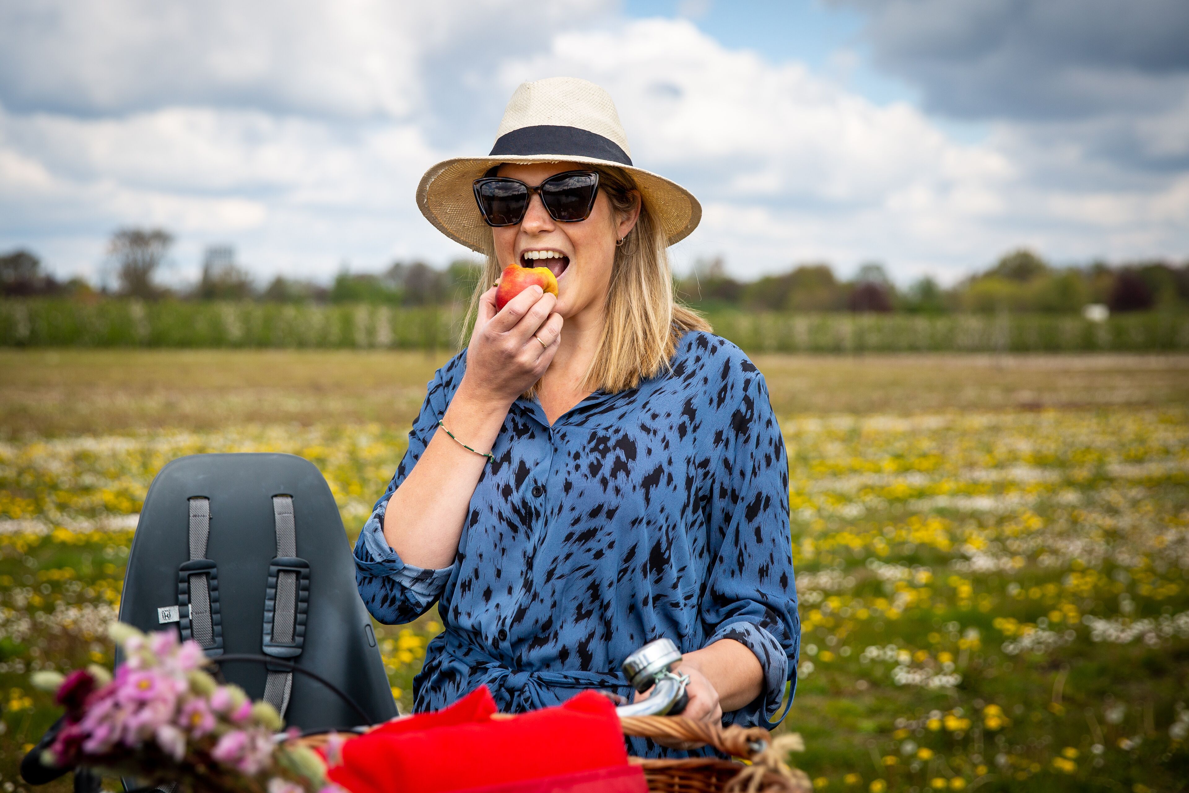 Iemand zit in een veld met een picknick, inclusief een mand en een camera.