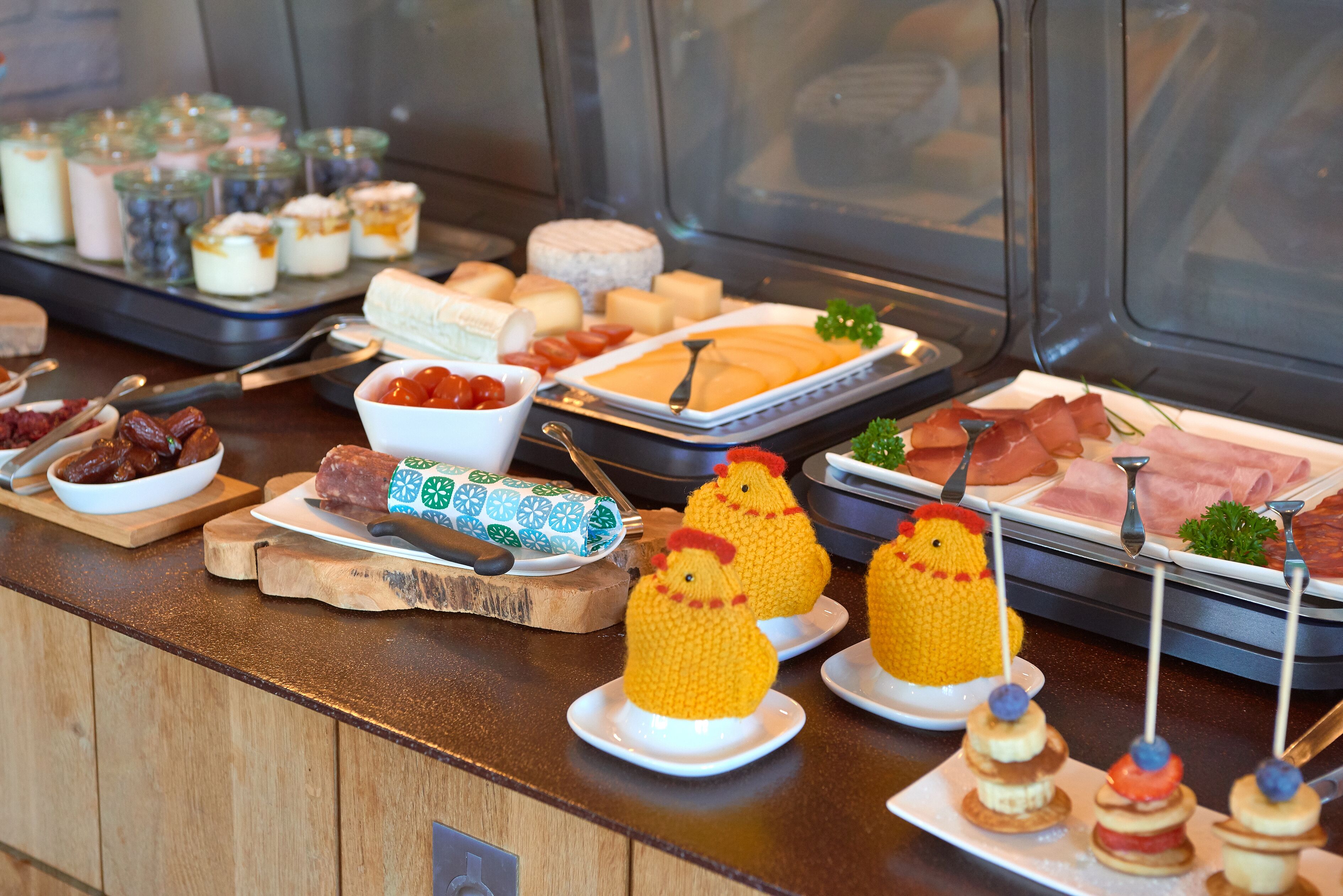 Een buffet met diverse soorten eten, waaronder vleeswaren, kazen en desserts.