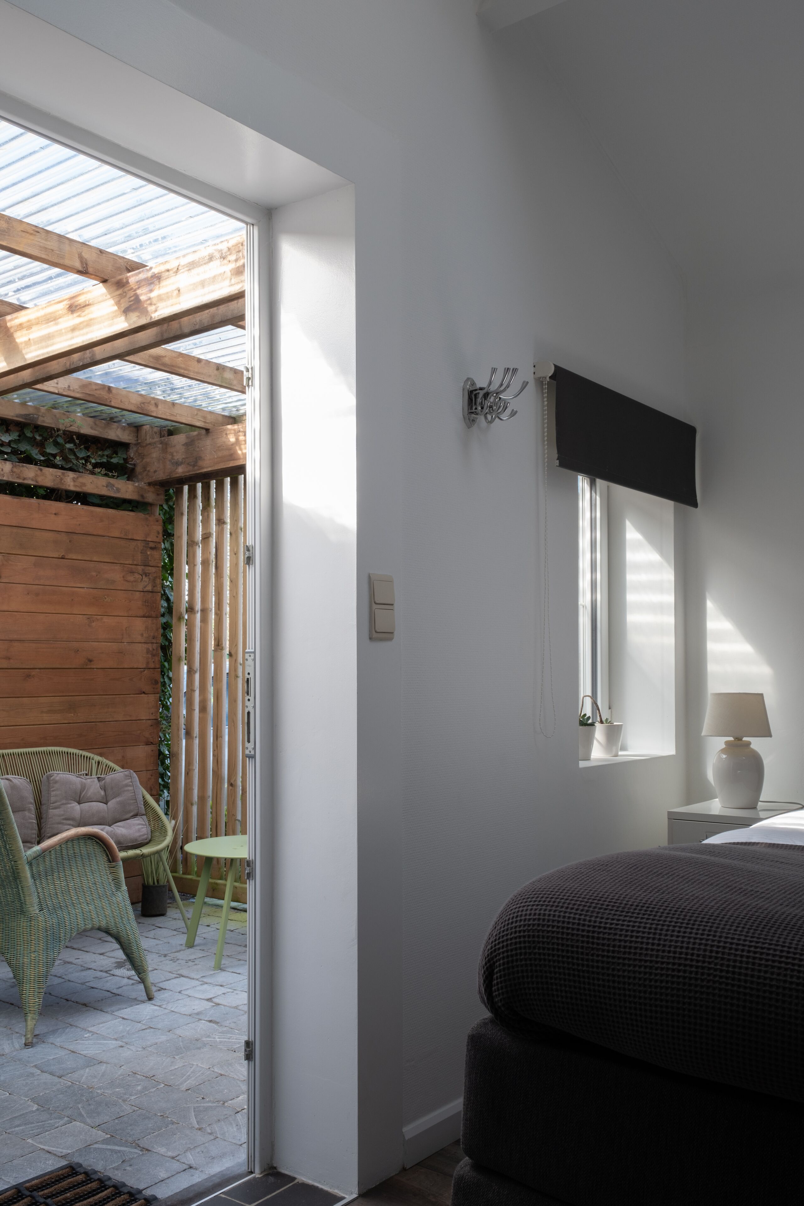 Een kamer met een bed, een raam, een stoel en een klein tafeltje.
