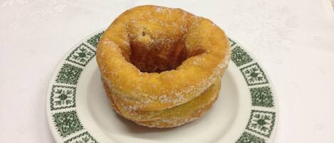 Un donut glaçat sol sobre un plat blanc amb dibuixos verds.