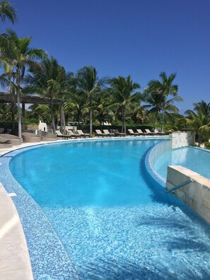 A clear blue swimming pool with lounge chairs and palm trees. - Tu Mirada al Mar Beachfront Tower & Spa (Cancun)