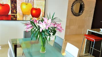 Un comedor moderno con una mesa de vidrio, sillas y un jarrón de flores.