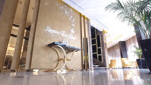 A hotel entrance with a modern design, featuring a reception desk and a sign that reads "Lusson De Estiva Suites Hotel." - Lumiere Des Etoile (Salmiya)