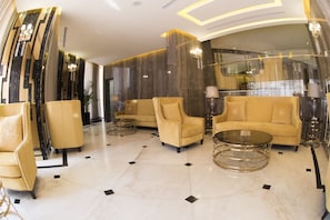 A luxurious lobby with a marble floor, high-end sofas, armchairs, and a glass coffee table.