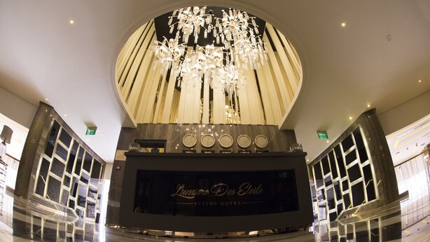 A hotel lobby with a large chandelier, a reception desk, and a sign reading "Lumiere Des Etoiles Suites Hotel". - Lumiere Des Etoile (Salmiya)