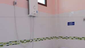 Une petite salle de bain avec des toilettes, une douche et une fenêtre.