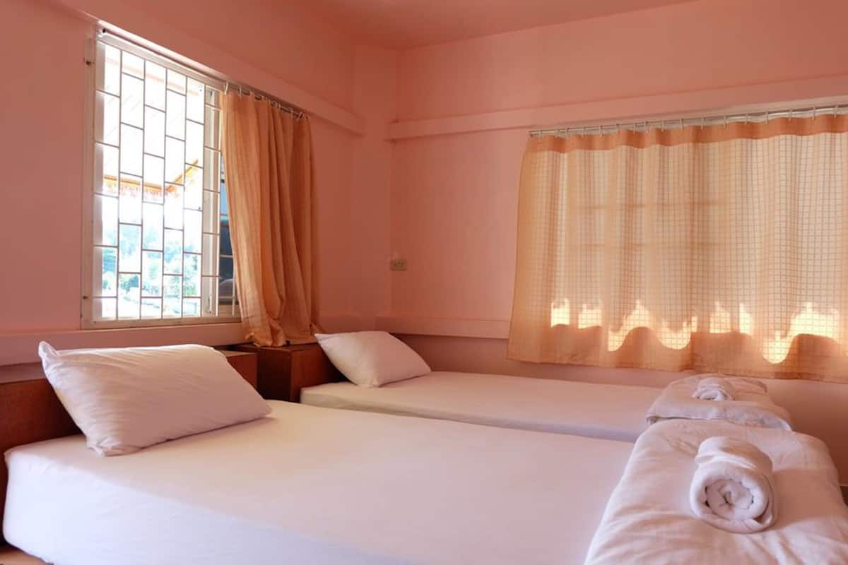 A room with two single beds, a window with a view, and a curtain.