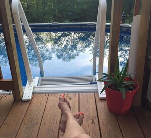 A wooden deck with a pool view, a potted plant, and a pool ladder. - Pocono private retreat (East Stroudsburg)