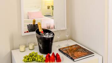 Un tocador blanco con espejo, un libro titulado 'Doma de arte', un cubo para champán, copas y un plato con uvas y fresas.