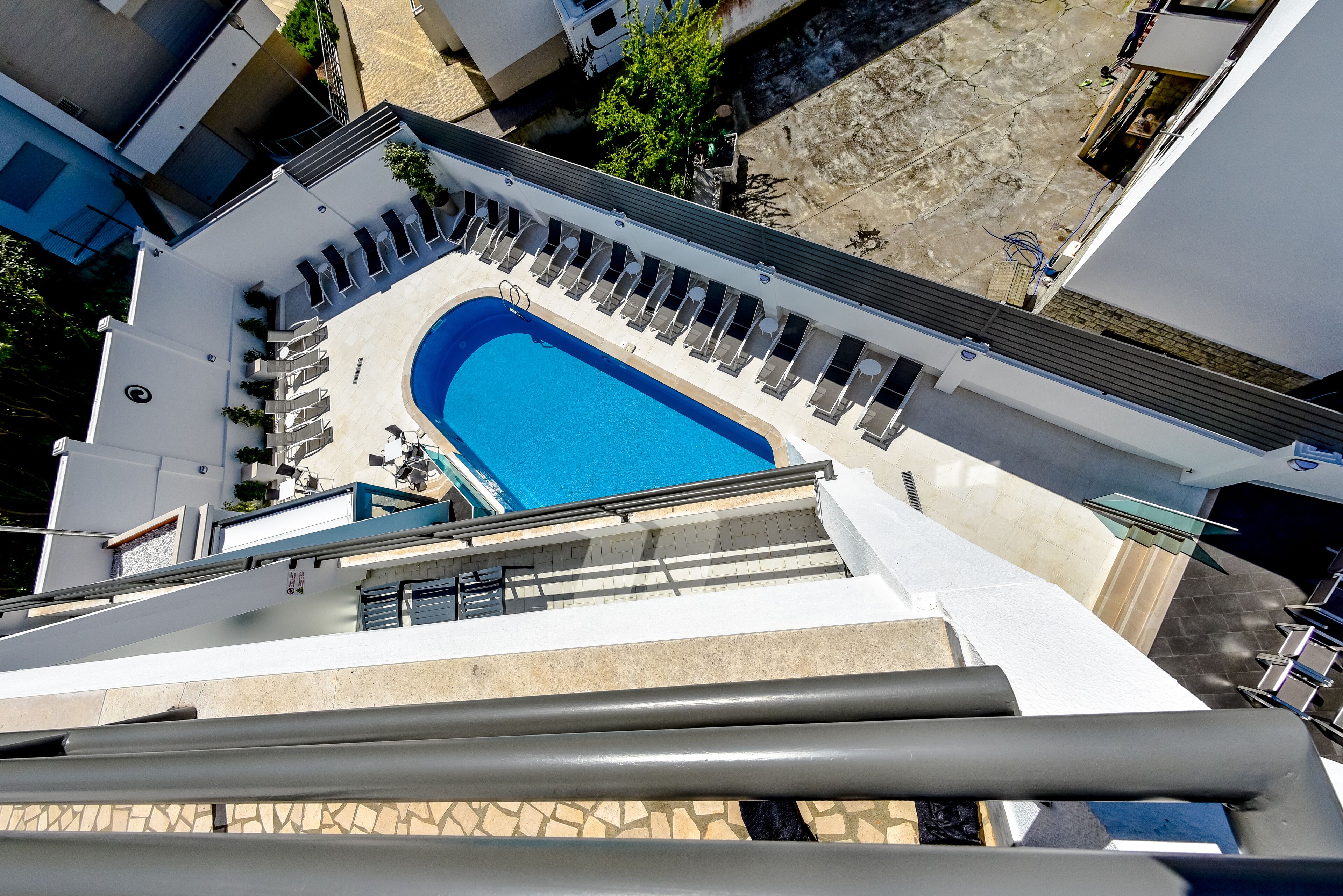 A rooftop swimming pool with lounge chairs and a clear blue pool.