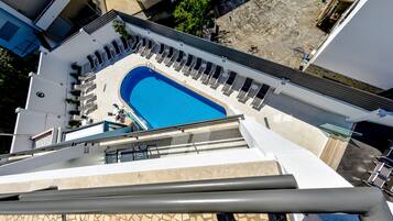 A rooftop swimming pool with lounge chairs and a clear blue pool.