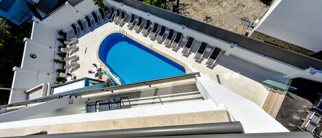 Una piscina en la azotea con sillas de descanso y agua cristalina.