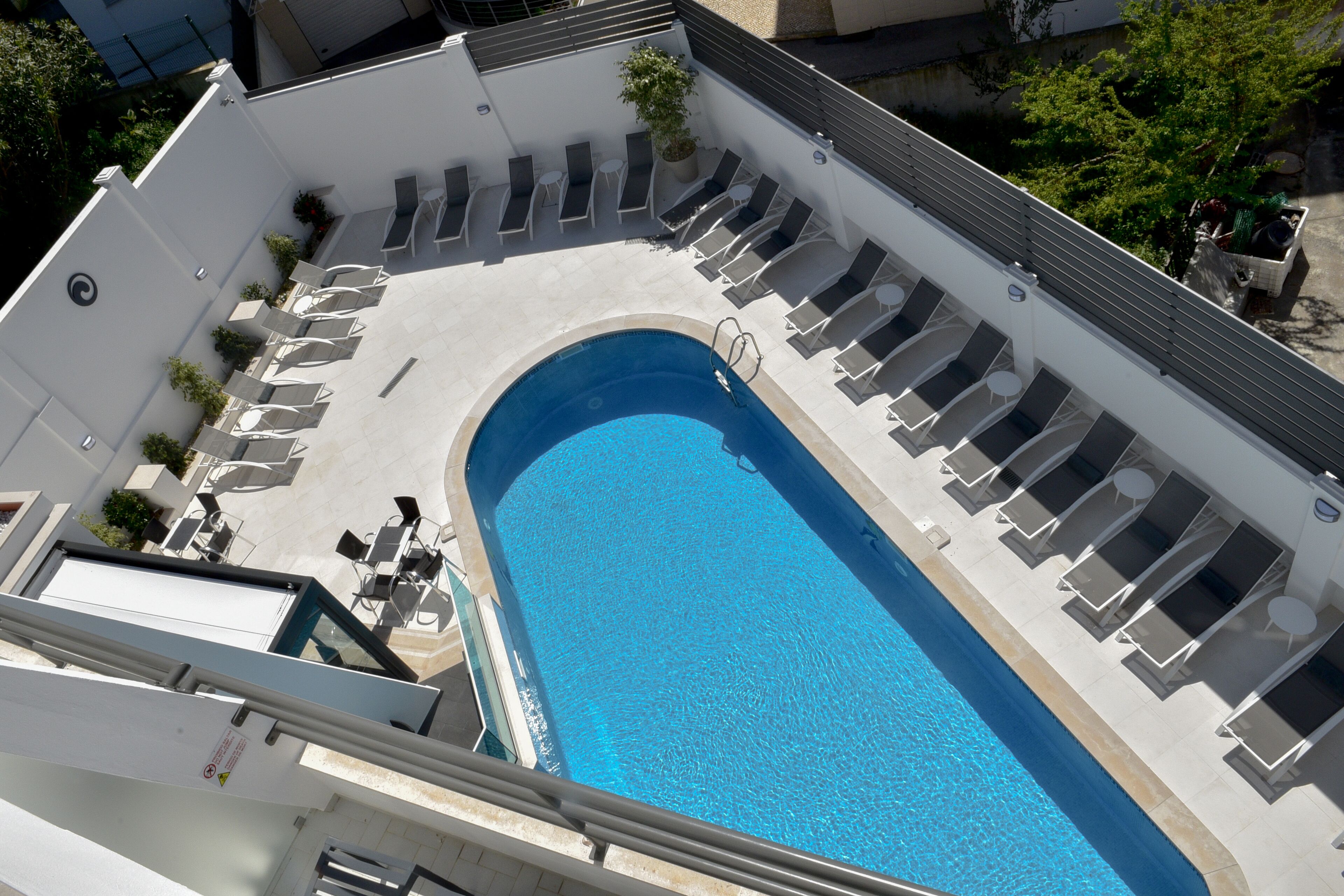 A rooftop swimming pool with lounge chairs and a small garden area.