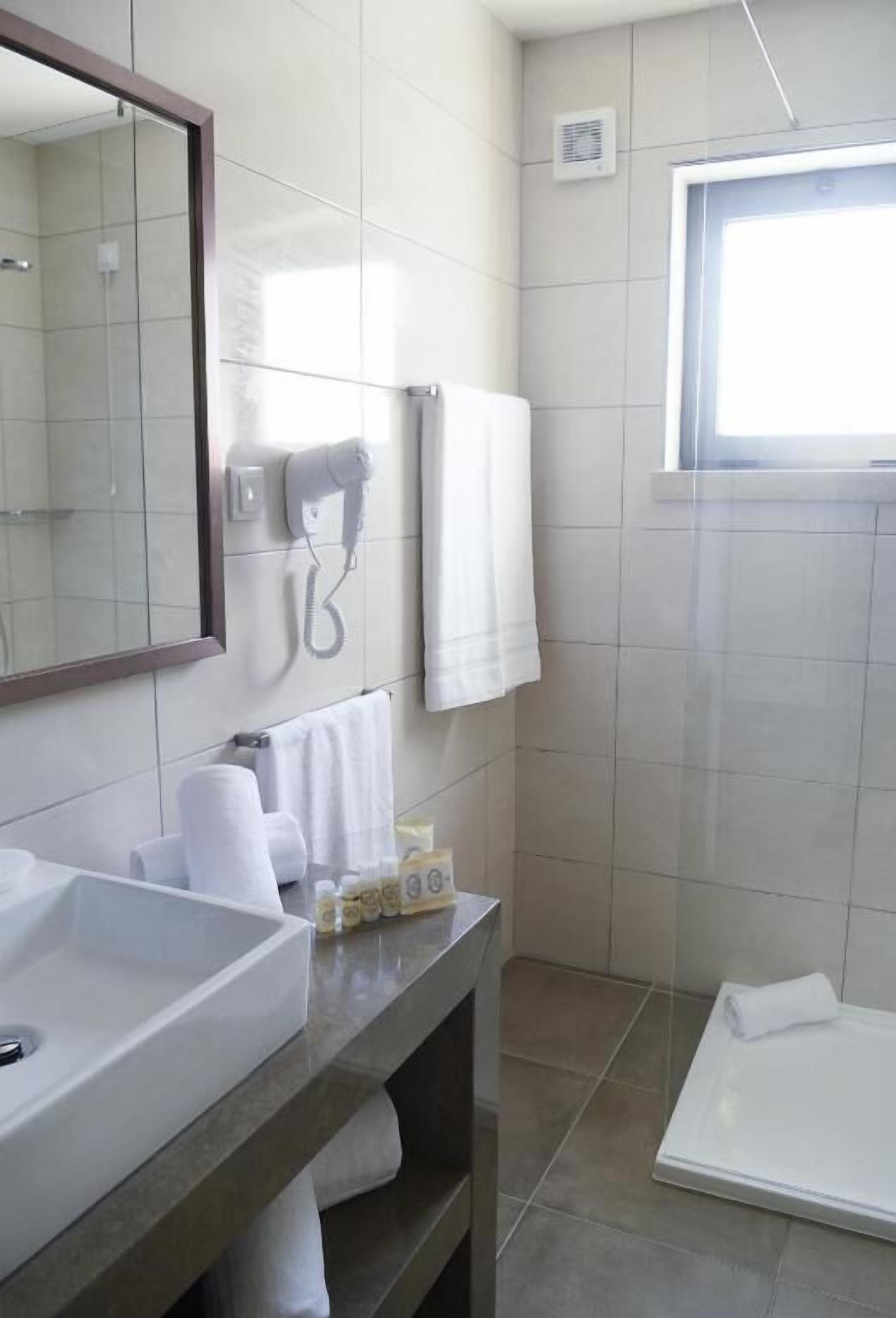 Un baño moderno con un espejo grande, un lavabo, toallero y zona de ducha.