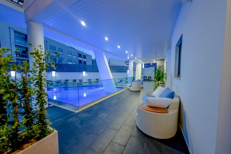 Una piscina al aire libre, sombrillas, sillones reclinables de piscina