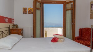 Een slaapkamer met een bed, een stoel en uitzicht op zee.