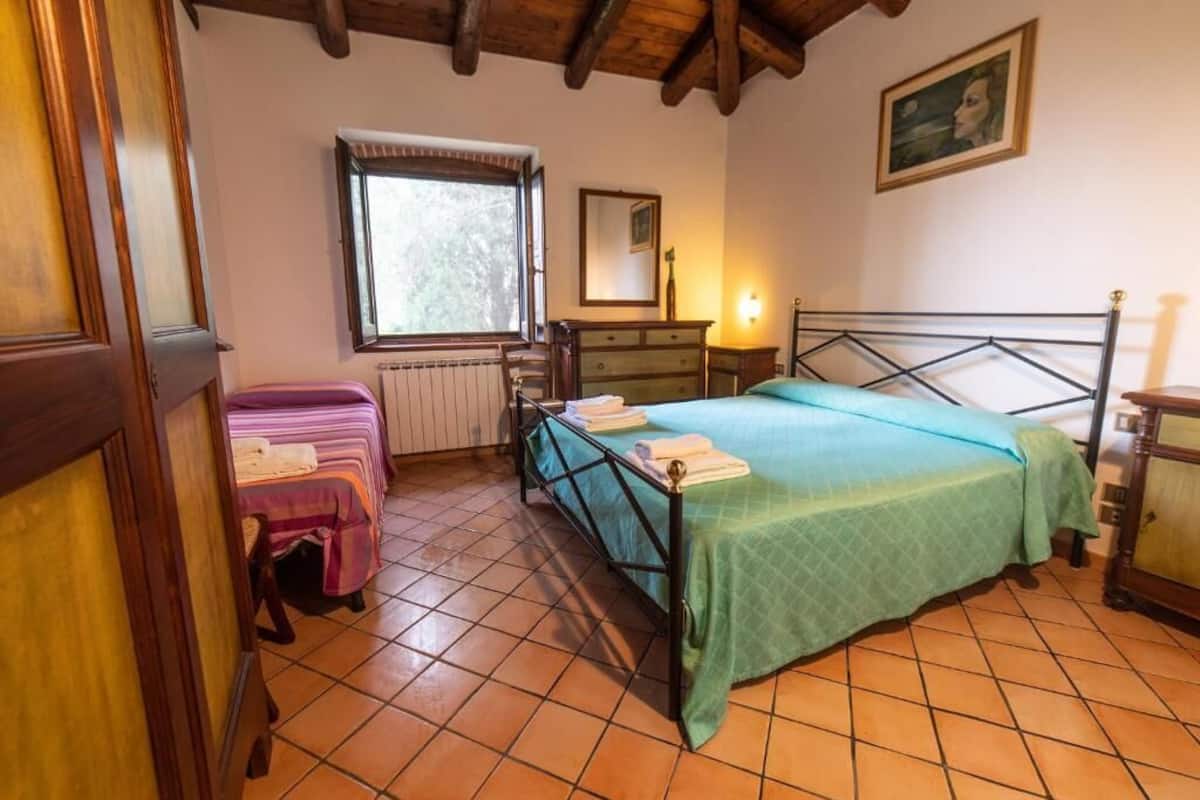 Une chambre à coucher avec un lit, une commode, une fenêtre et un radiateur.