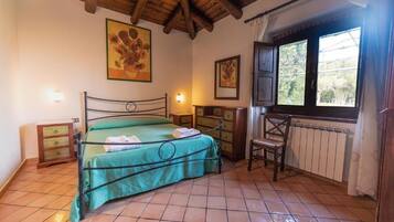 A bedroom with a bed, a wooden chair, a dresser, and a window with curtains.