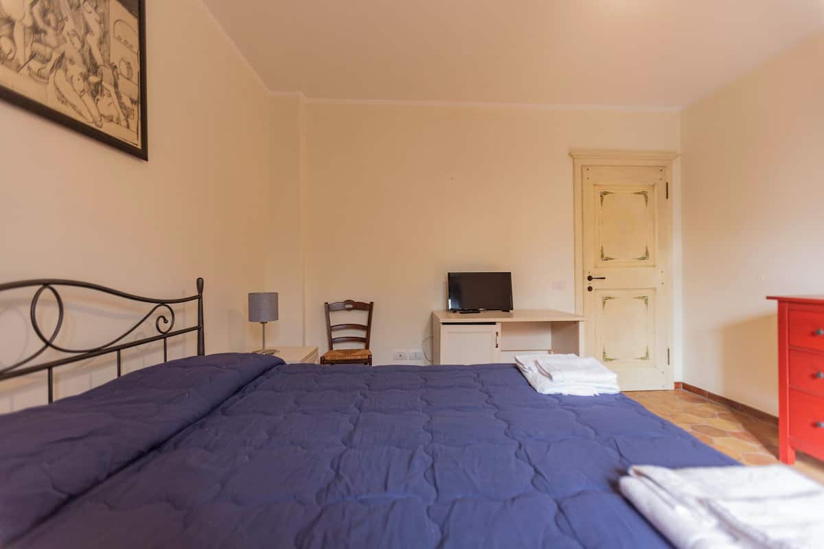 Une chambre à coucher comprenant un lit, un téléviseur posé sur un meuble, une chaise, un bureau et une armoire.