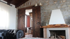 Una sala de estar con una pared de piedra, una chimenea, un sofá de cuero negro y una puerta de madera.