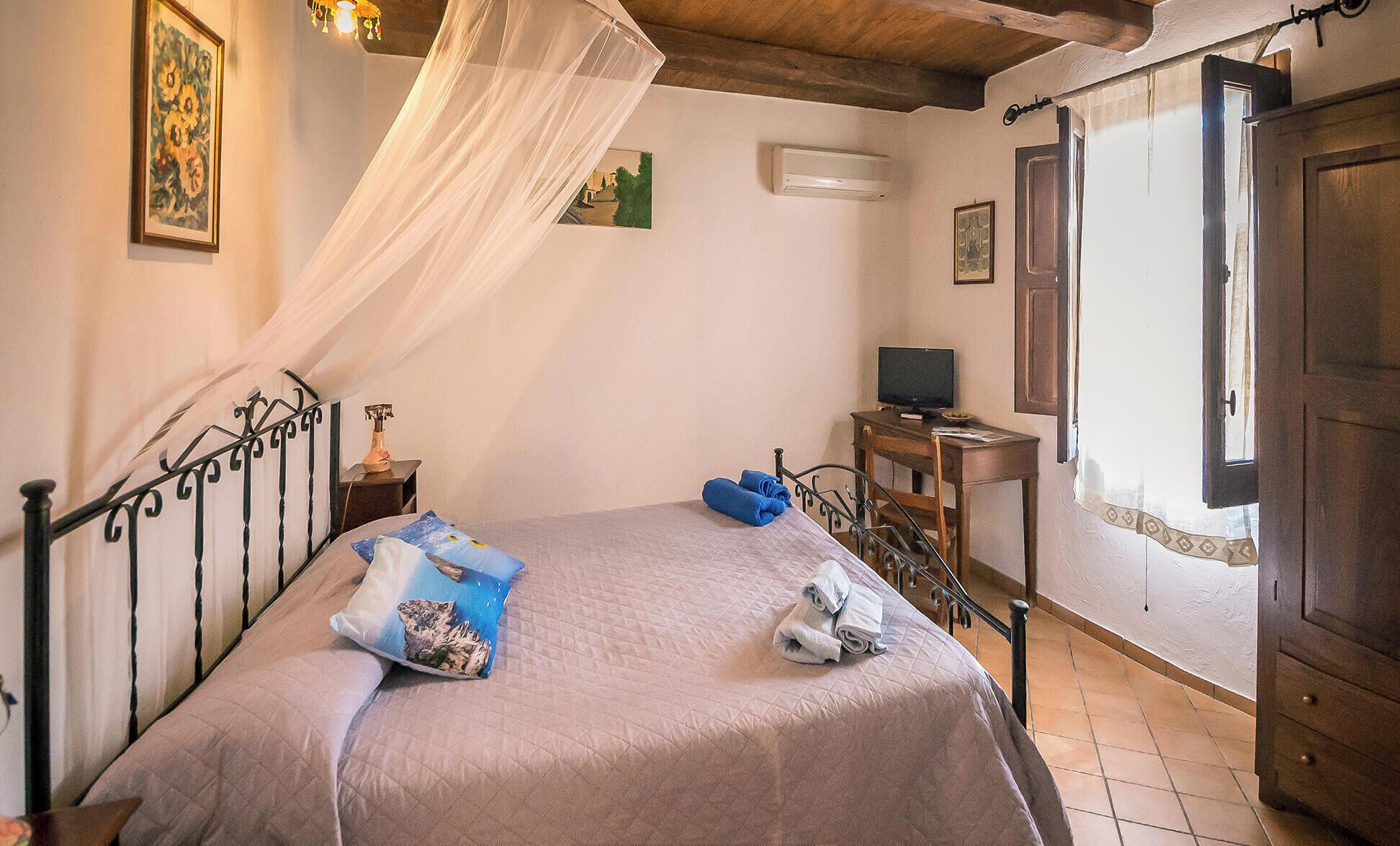 Un dormitorio con cama, televisor, escritorio y puerta.