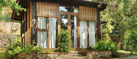 A rustic wooden cabin with large windows, stone walls, and a stone pathway leading to the entrance.