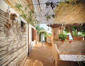 A covered outdoor area with a brick pathway, a wooden bench, and a table with chairs. - B&B La Torretta (Maratea)