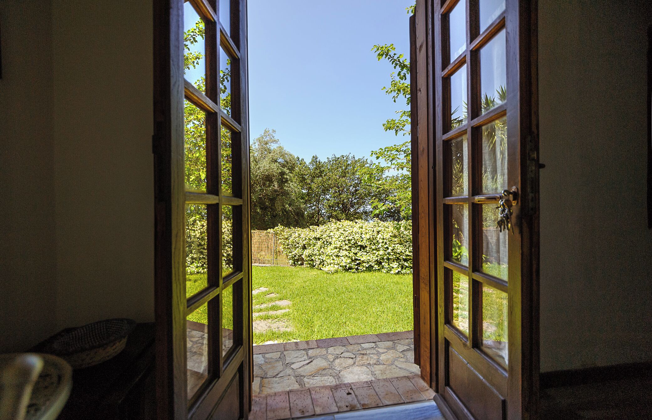 An open doorway leading to a well-maintained garden with a stone pathway.