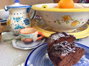 A table with a teapot, a bowl, a mug, and a plate with a piece of cake. - B&B La Torretta (Maratea)