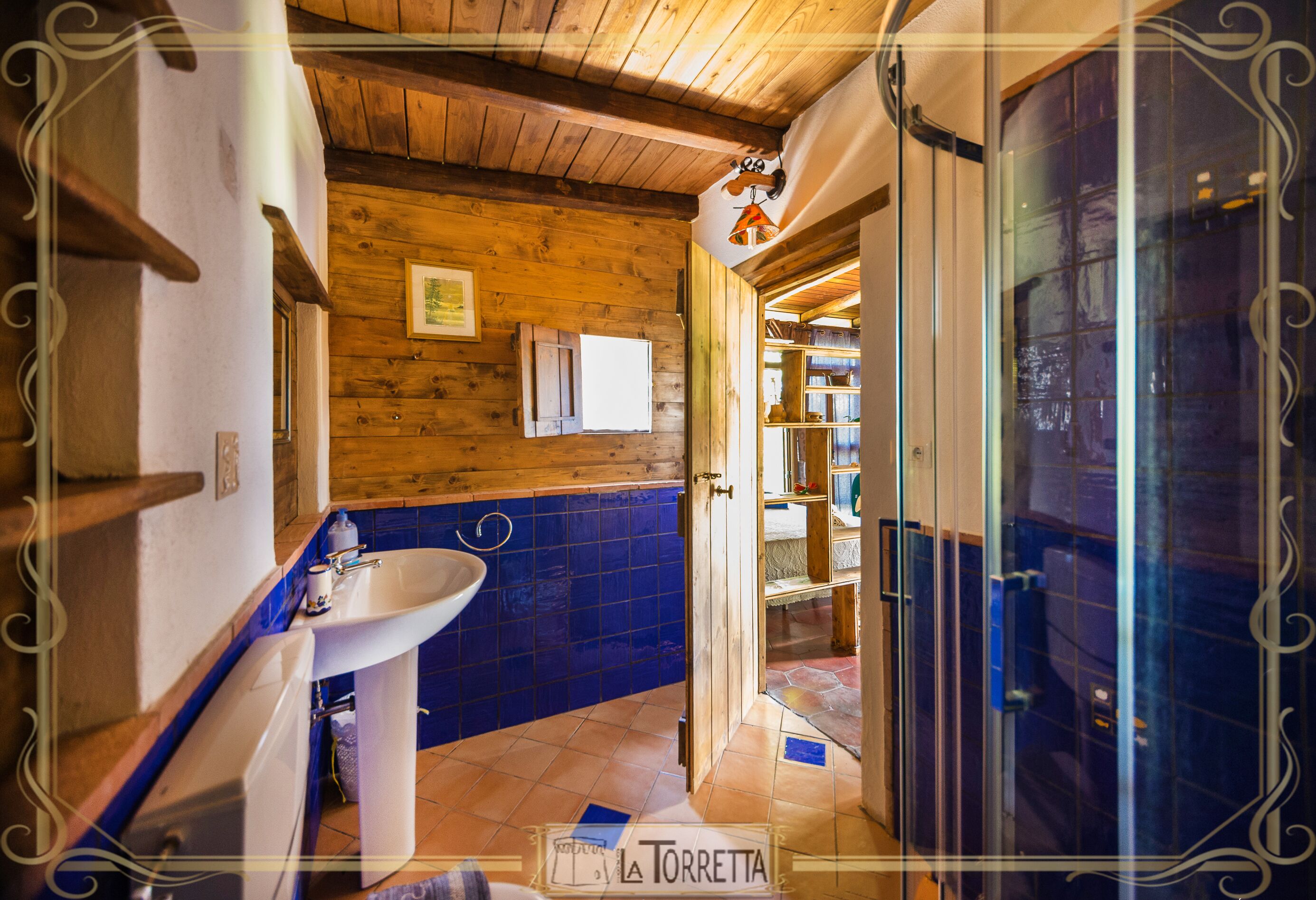 A bathroom with a wooden ceiling, a white sink, and blue-tiled walls.