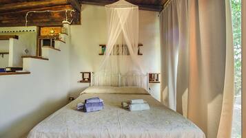 Une chambre à coucher comprenant un lit, un baldaquin, une table de chevet, une horloge murale et une fenêtre avec des rideaux.